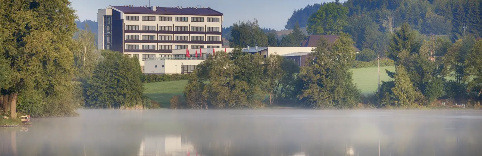 Hotel Skalský dvůr nad hladinou rybníka v ranní mlze